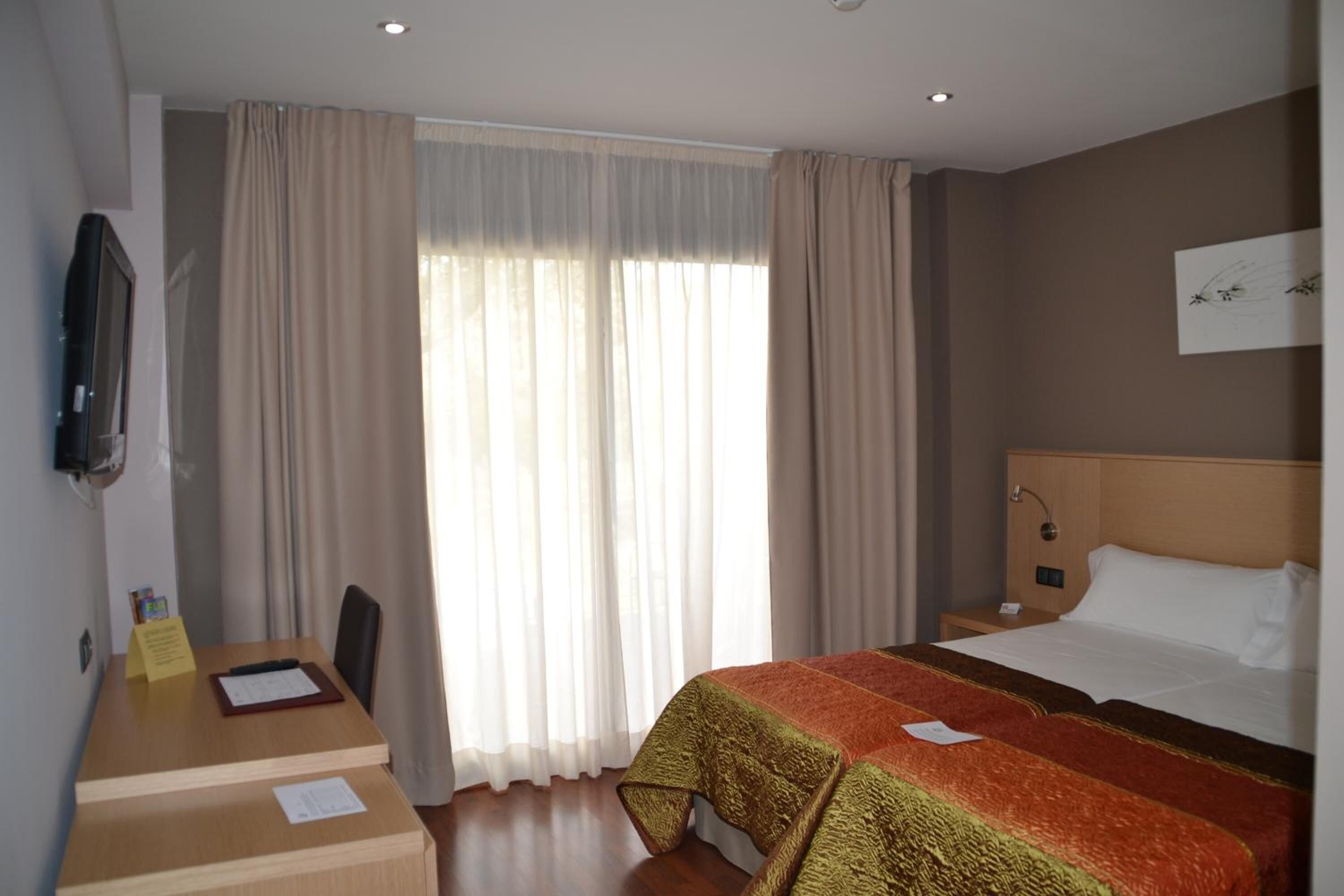 Une chambre d’hôtel avec un lit, un bureau et une télévision.