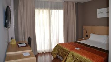 Une chambre d’hôtel avec un lit, un bureau et une télévision.
