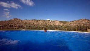 Una piscina al aire libre, sombrillas, sillones reclinables de piscina