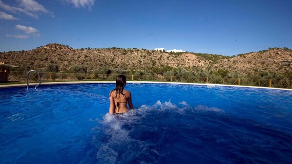 Una piscina al aire libre, sombrillas, tumbonas