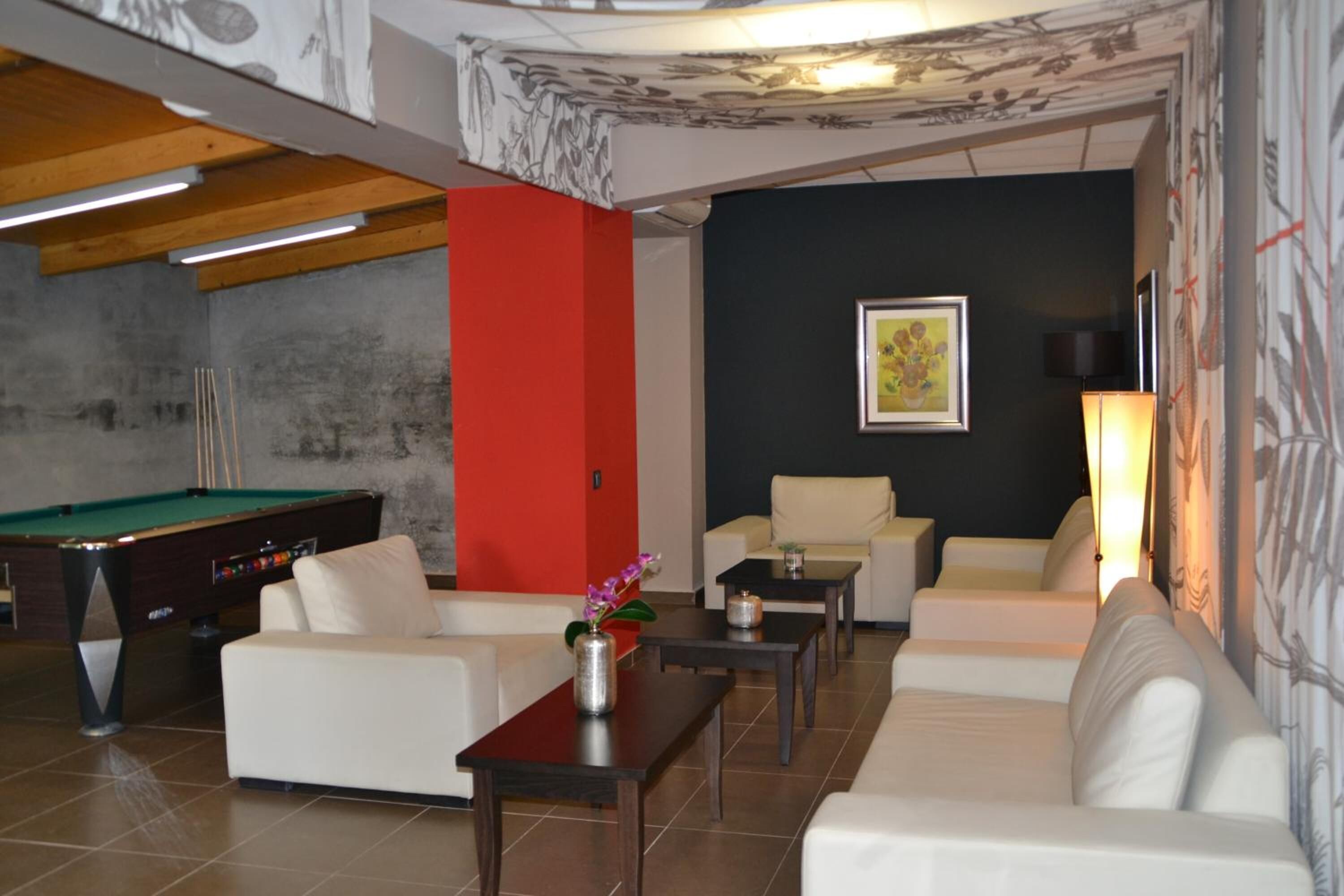 A modern living room with a pool table, white sofas, and a dark accent wall.