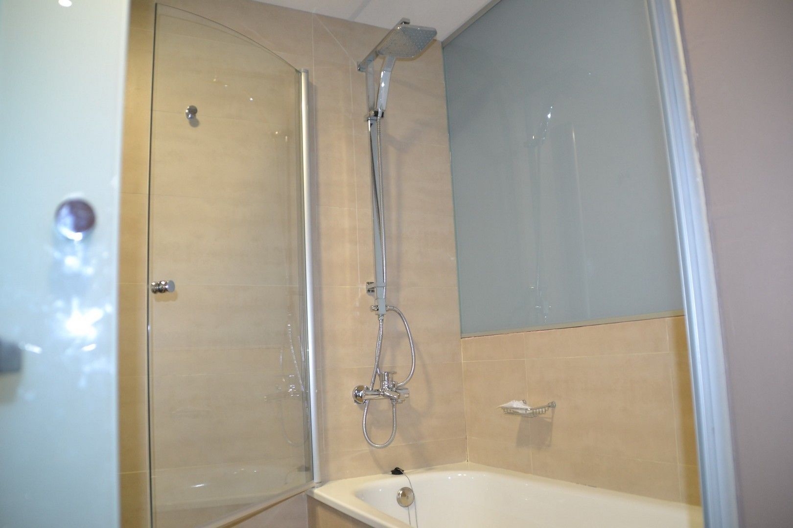 A bathroom with a glass-enclosed shower, a bathtub, and a mirror.