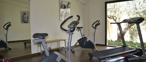 A gym with stationary bikes, a treadmill, and a bench.