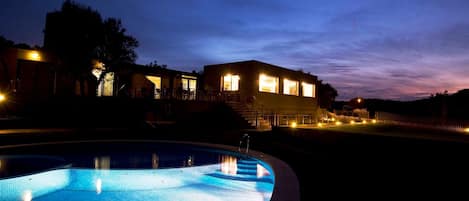 A modern building with a swimming pool at dusk.