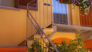 A staircase with orange steps leading to a landing with a metal railing. - Bel Sorriso Varese - Dormire Felice Rooms & Apartments (Varese)