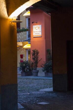 An entrance to a building with a sign for 'BelSorriso Varese' indicating a bed and breakfast. There are potted plants and a balcony with hanging lights. - Bel Sorriso Varese - Dormire Felice Rooms & Apartments (Varese)