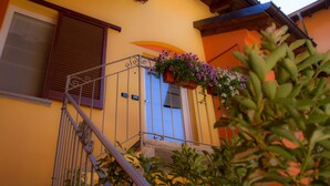 A yellow building with a blue door, a metal staircase, and a flower box on the balcony. - Bel Sorriso Varese - Dormire Felice Rooms & Apartments (Varese)