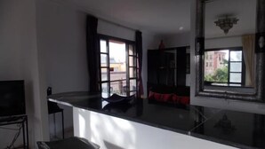 A modern living room with a black countertop, a TV, and a large mirror. - Appart avec vue Jardin-Majorelle (Marrakech)