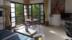 A room with a dining table, chairs, a sofa, a TV, and a painting on the wall. - Appart avec vue Jardin-Majorelle (Marrakech)