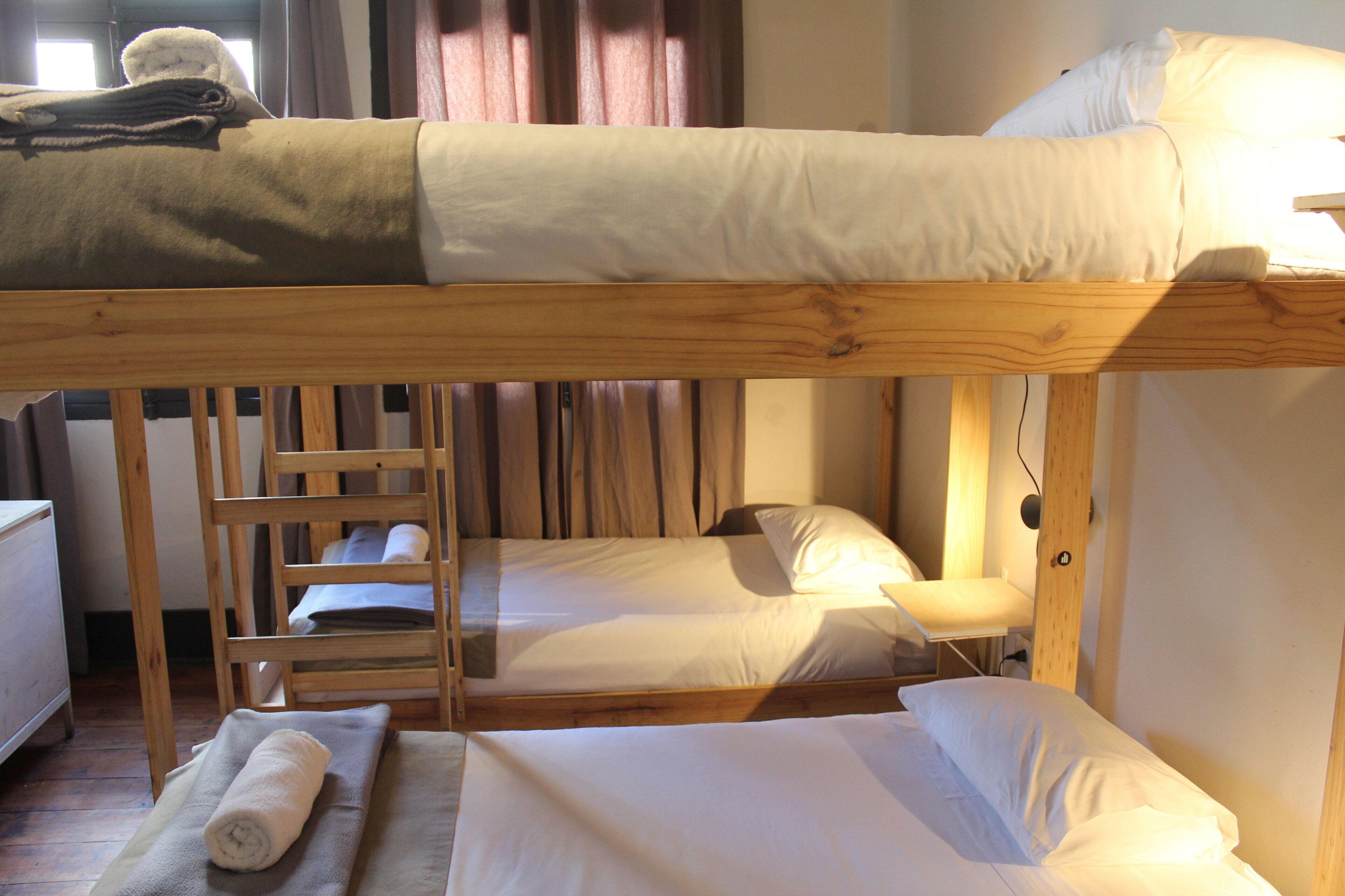 A bunk bed room with a ladder, a small table, and a rolled towel on the floor.