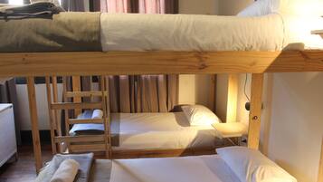 A bunk bed room with a ladder, a small table, and a rolled towel on the floor.