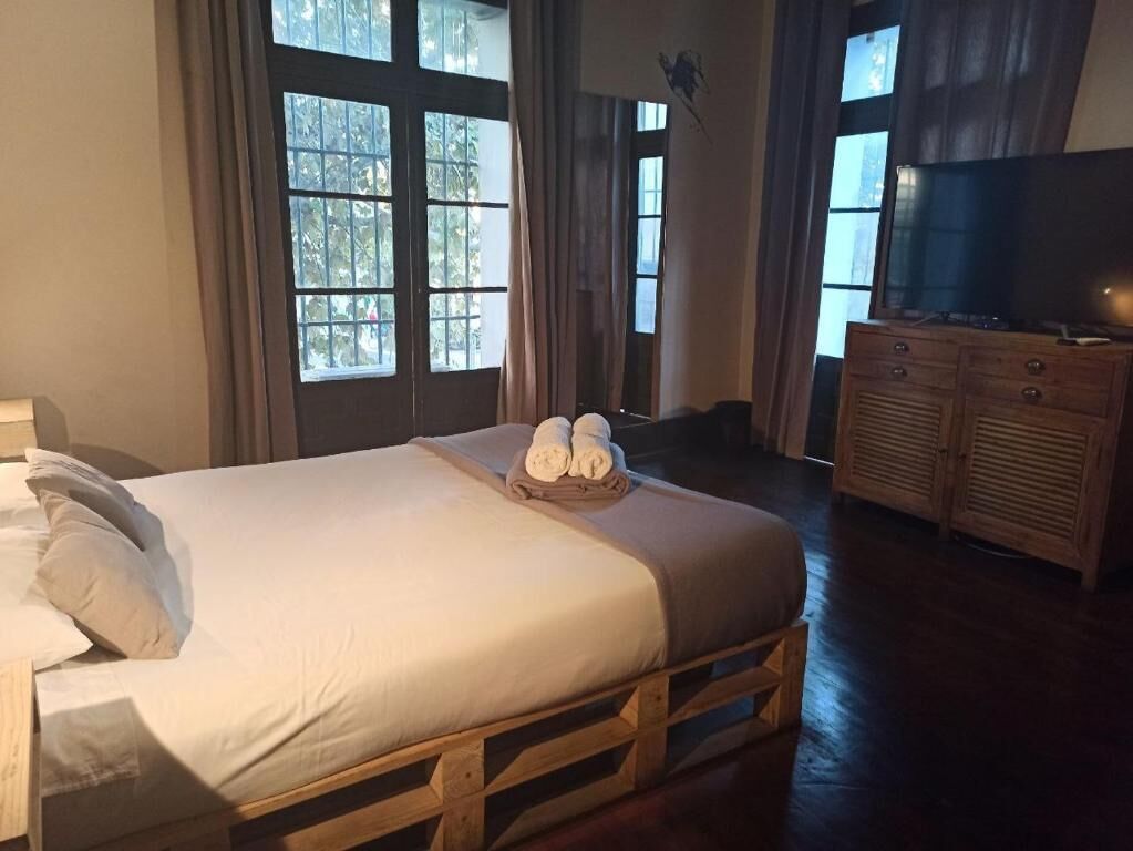 A neatly made bed with towels, a wooden dresser, and a television.