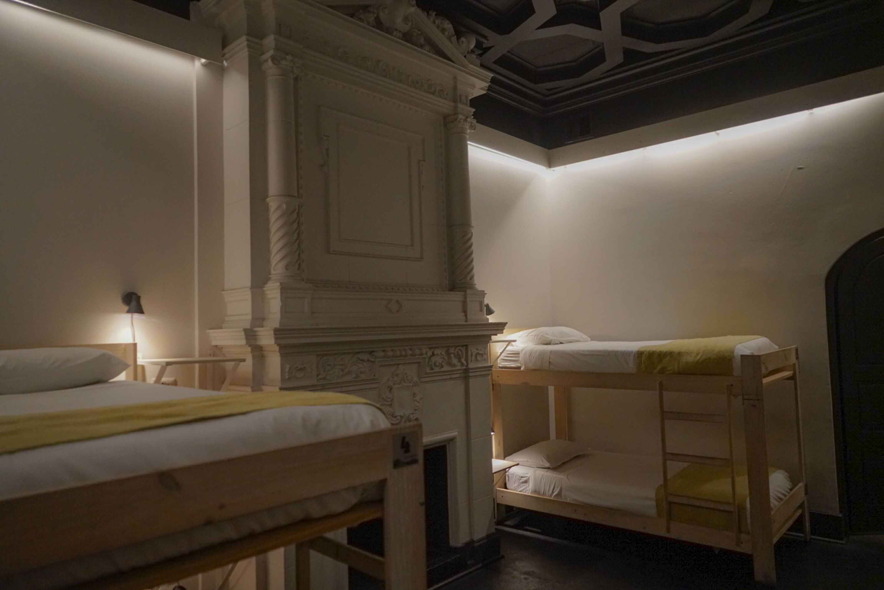 A room with two bunk beds, a fireplace, and a decorative ceiling.