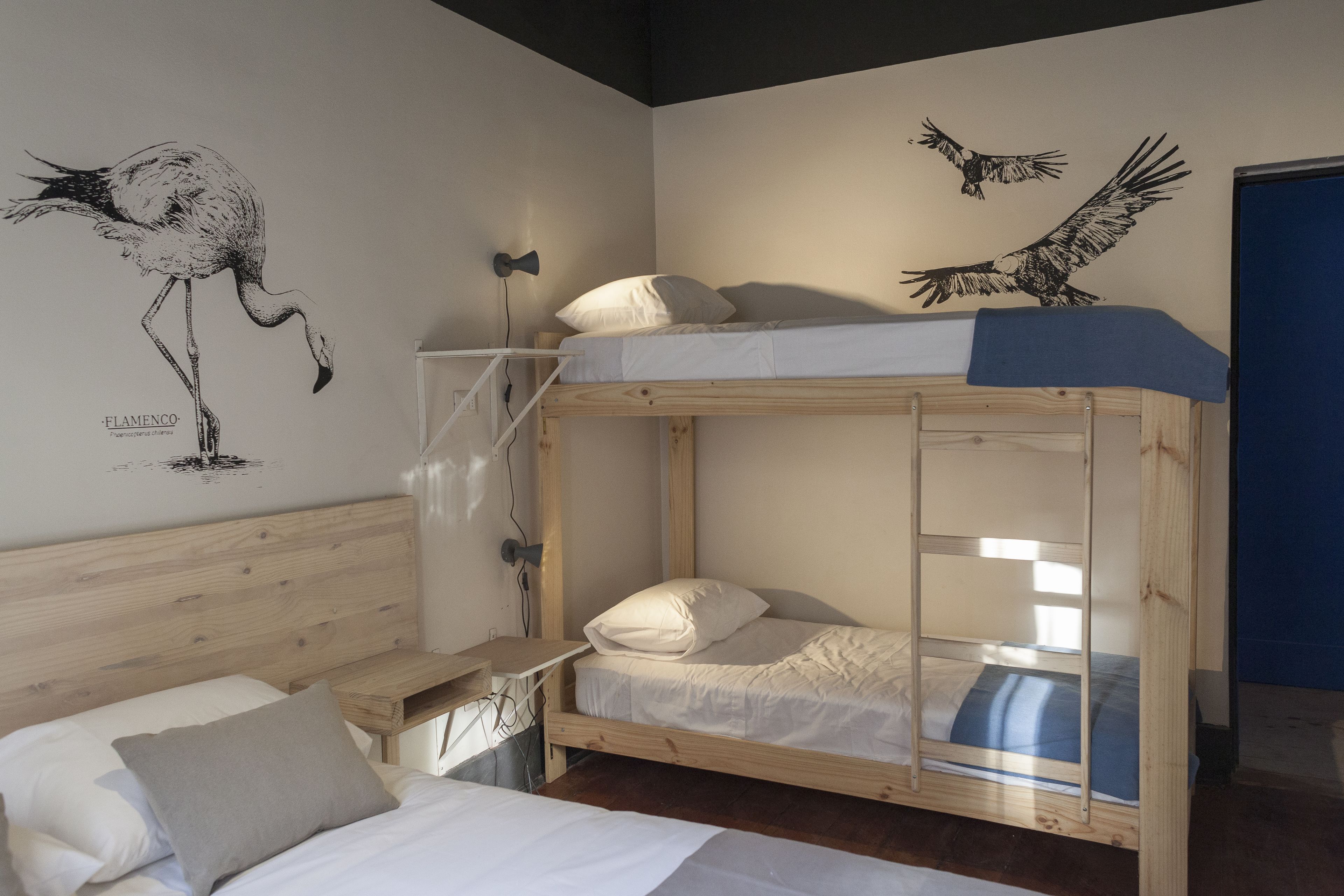 A bunk bed room with a wooden headboard, a desk, and a wall mural of a flamingo and an eagle.