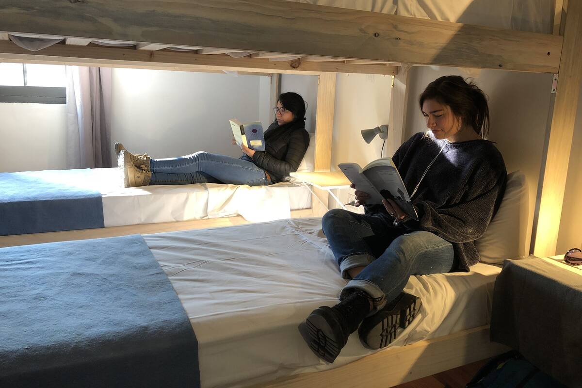 A bunk bed room with two beds, a window, and a bedside lamp.