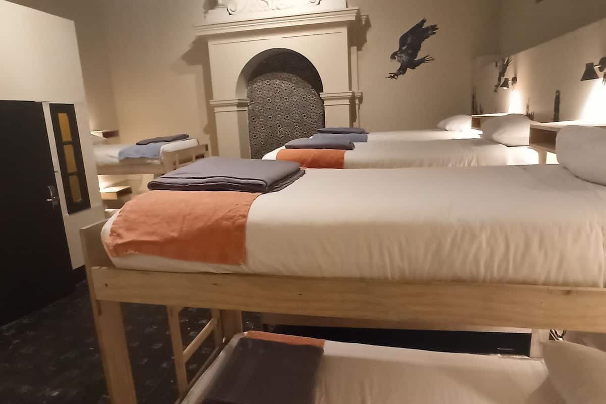 A hotel room with bunk beds, a fireplace, and a wall-mounted lamp.