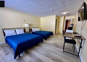 A hotel room with two beds, a desk, a chair, a TV, and a coffee machine. - Spanish River Inn (Spanish)