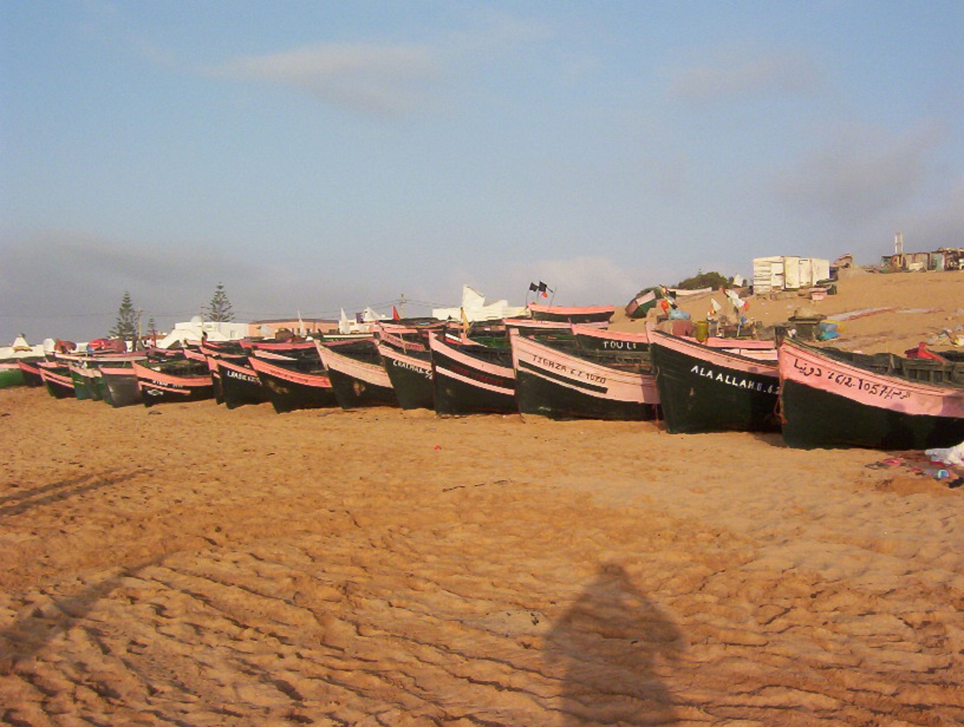 A row of boats lined up on a sandy beach.