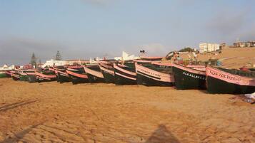 A row of boats lined up on a sandy beach.