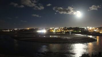Vista nocturna de una zona ribereña con edificios iluminados al fondo.