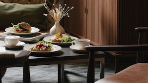 A dining area with a table set for a meal, a sofa, and a cabinet with a sign.