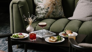 A dining table with plates of food, a drink, and a book.