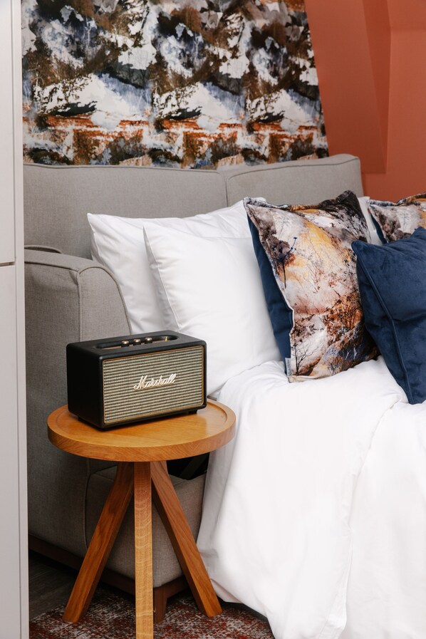 A bed with white bedding, a patterned pillow, and a Marshall speaker on a wooden side table. - Heeton Concept Aparthotel Edinburgh Queen Street (Edinburgh)