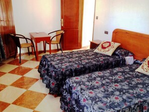 Una habitación de hotel con dos camas, una mesita pequeña y una silla.