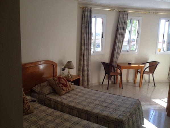 A room with two beds, a desk, and two chairs. - Motel Paris Dakar (Al Aaroui)