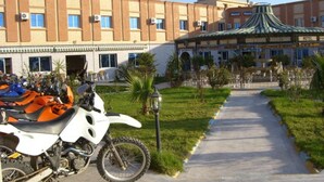 Un hotel con un patio central, un área cubierta con techo a rayas y un camino pavimentado.