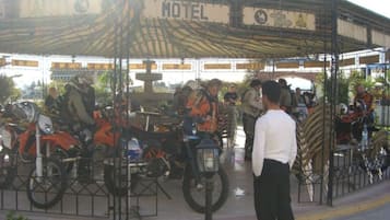 Un espace extérieur abrité, sur lequel on peut lire l’inscription « Motel » sur une enseigne, et où plusieurs motos sont garées.