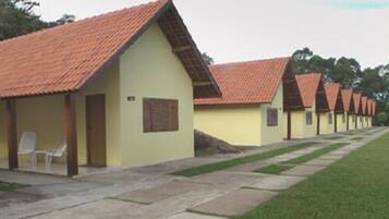 A row of single-story buildings with red-tiled roofs and light yellow walls, arranged in a straight line with a paved walkway between them.