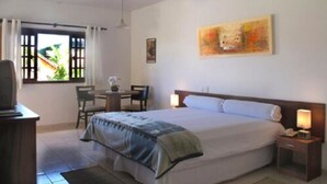 A bedroom with a bed, bedside table, lamp, chair, desk, and a window with curtains. - Resort Monte das Oliveiras (Joanópolis)