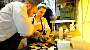 Un chef est en train de préparer un plat dans une cuisine où l’on peut voir divers ustensiles et ingrédients.