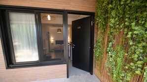 Une entrée d’hôtel moderne avec une porte en verre, un mur en bois et un mur en bambou.