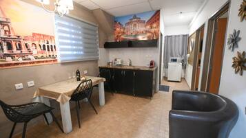 Cocina compacta con una mesa de comedor, sillas, un refrigerador y un microondas.