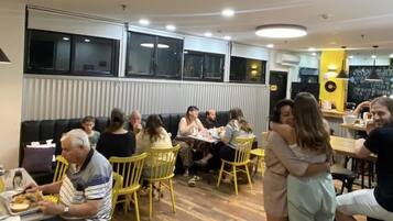 A restaurant with wooden flooring, yellow chairs, and a group of people dining.