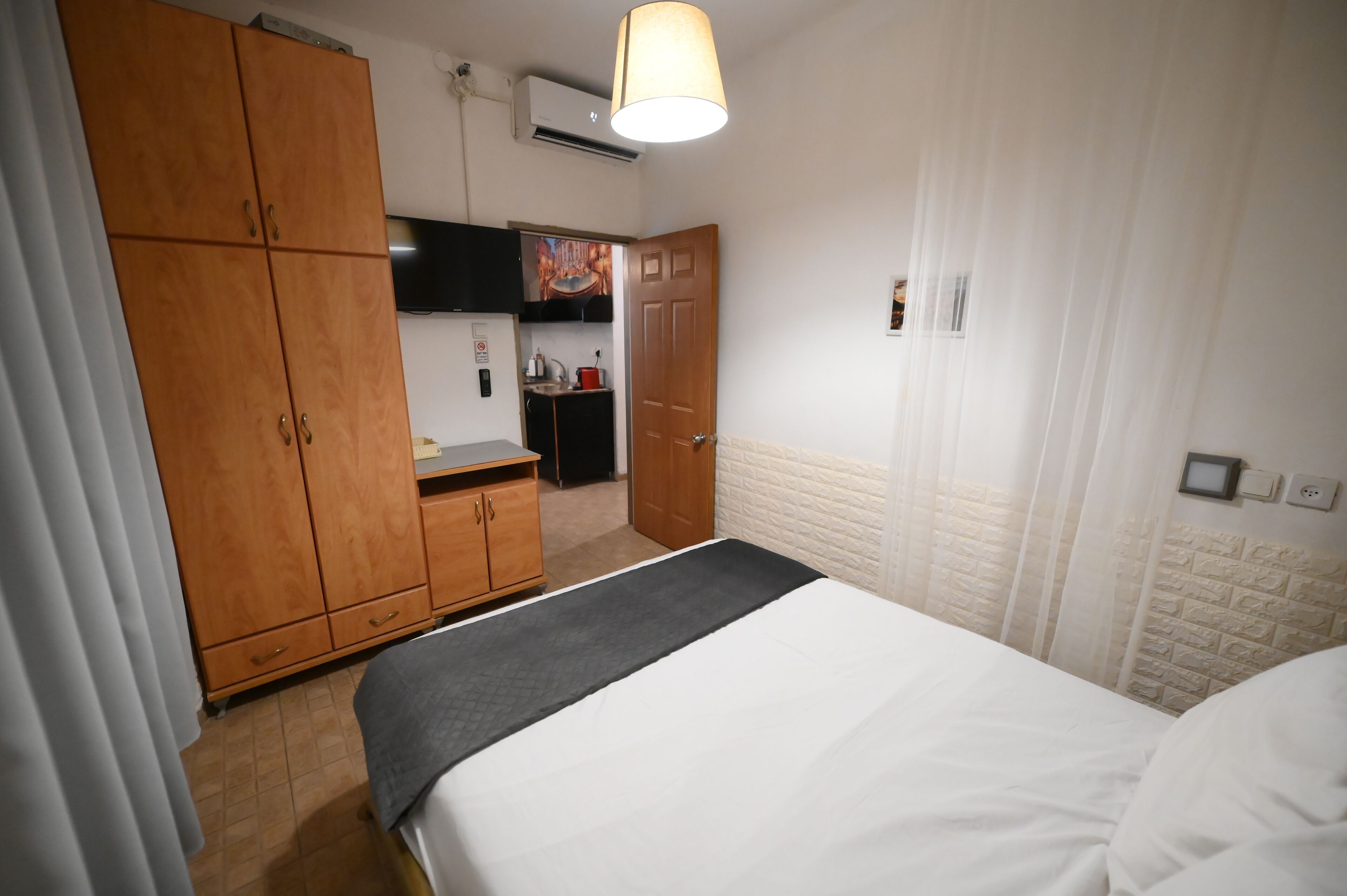 Una habitación de hotel con cama, armario, kitchenette y baño.