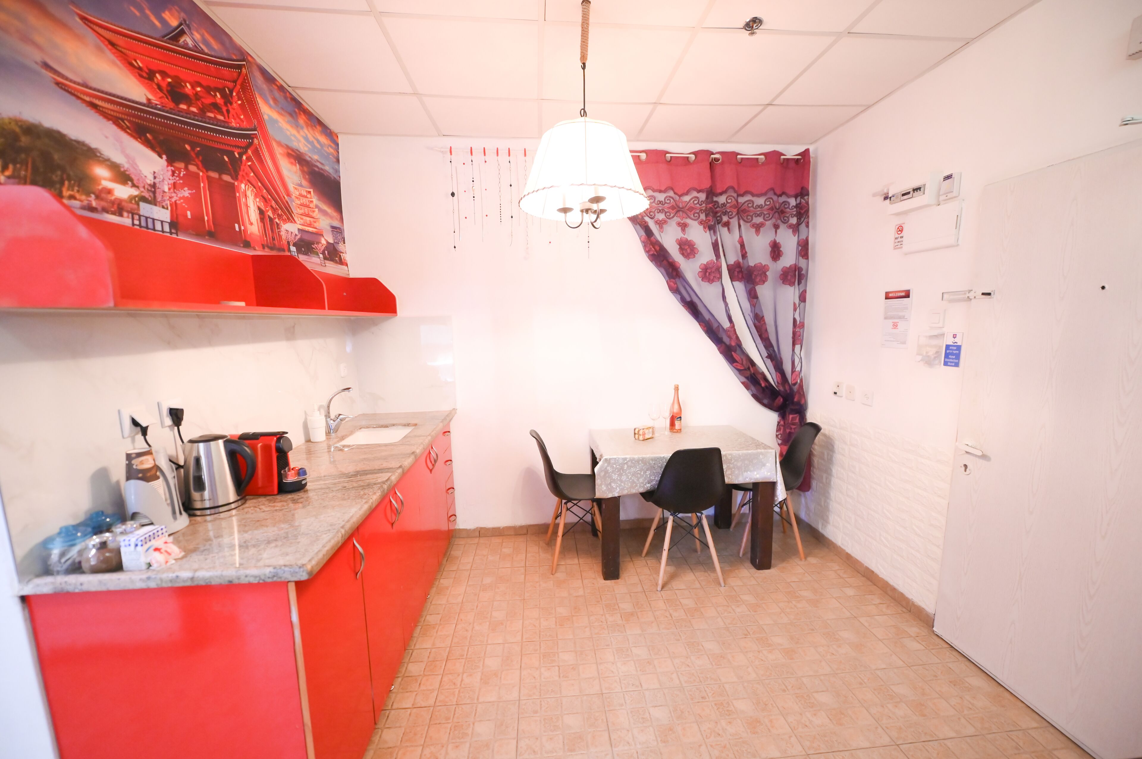 A compact kitchen with a dining table, chairs, and a hanging light fixture.