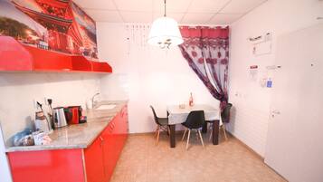 A compact kitchen with a dining table, chairs, and a hanging light fixture.