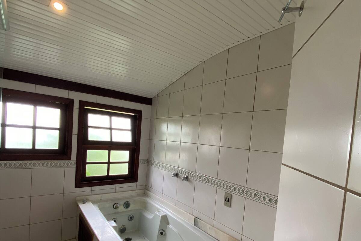 A bathroom with a bathtub, a window, and tiled walls.