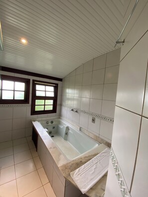 A bathroom with a bathtub, a window, and tiled walls.