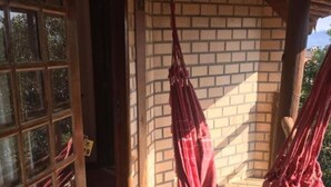 Une véranda en bois avec un hamac et un mur en briques.