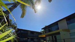 Une piscine dotée d’une terrasse en bois, entourée de palmiers et bordée d’un bâtiment avec des balcons.