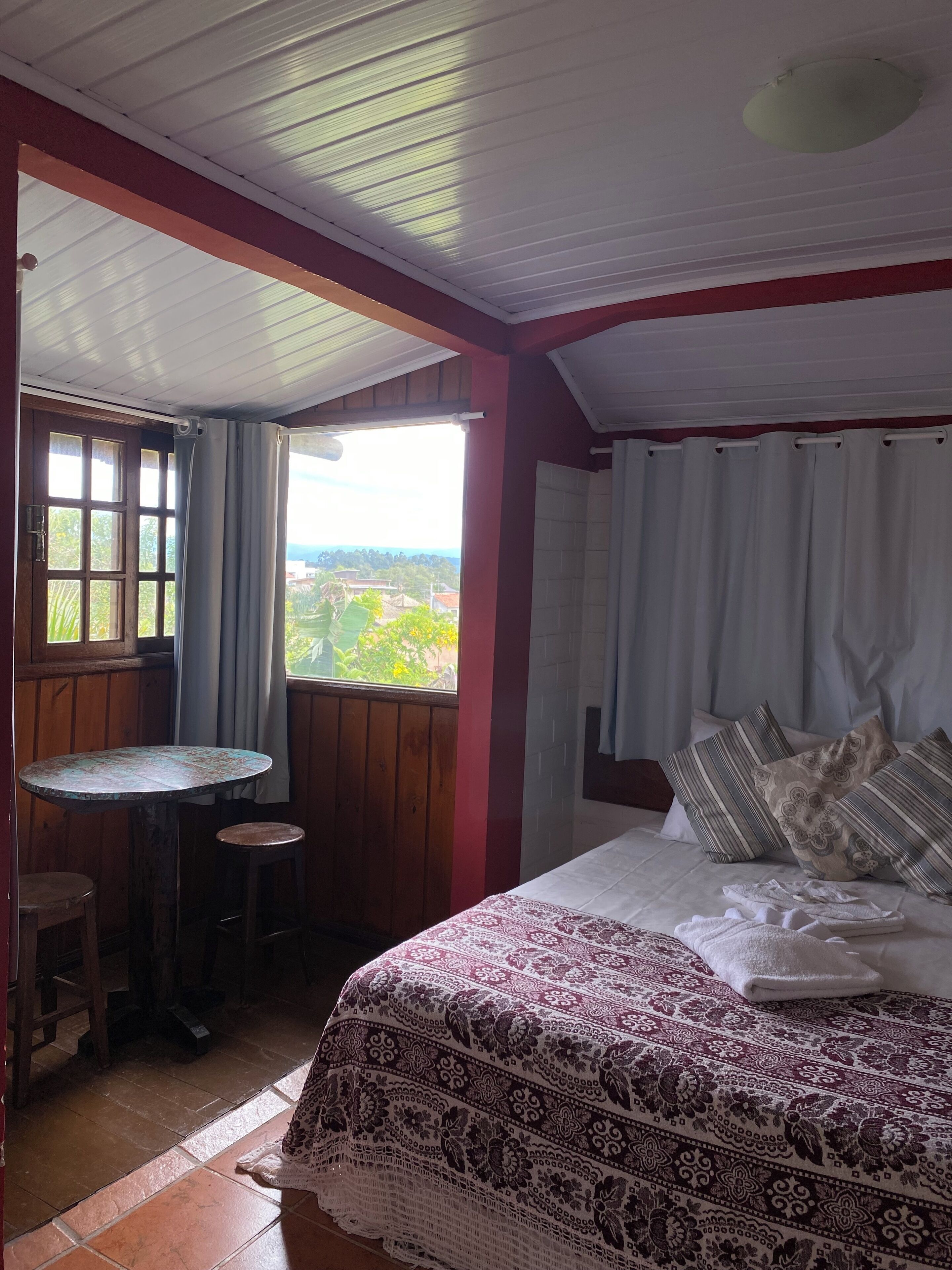 Ein Schlafzimmer mit einem Bett, einem kleinen Tisch und einem Fenster mit Vorhängen.