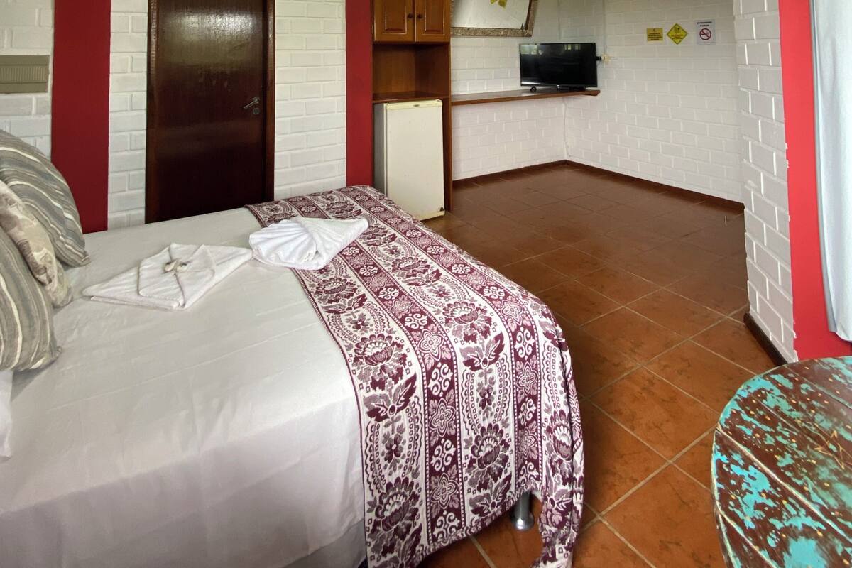 A bedroom with a bed, a small kitchenette, and a bathroom.