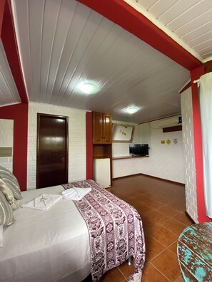 A bedroom with a bed, a small kitchenette, and a bathroom.