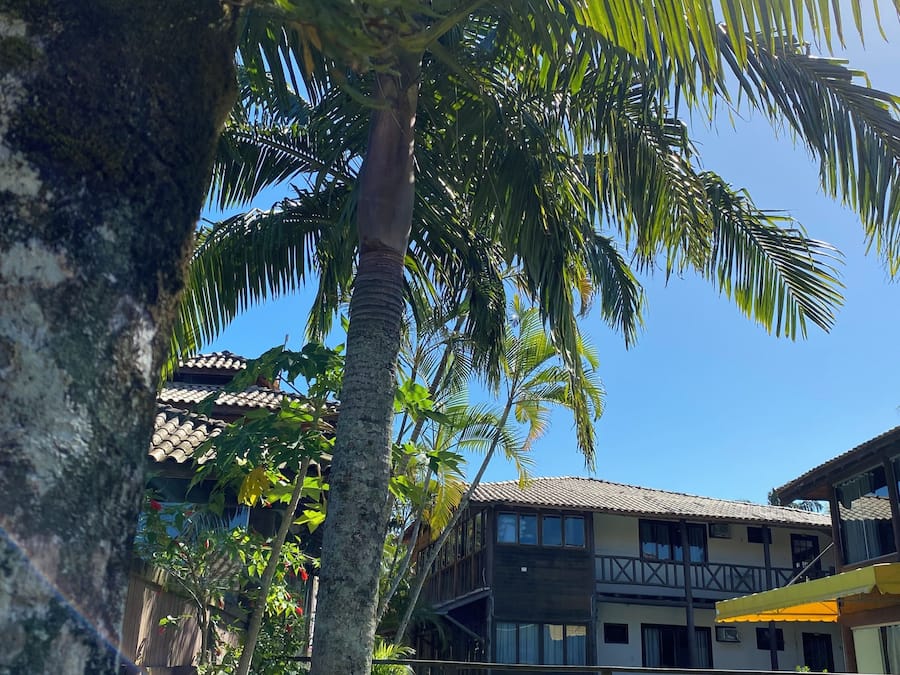 A pool area with a wooden deck, a bench, and a building with balconies in the background.