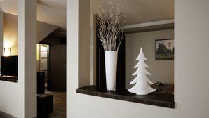 Un interior moderno con un florero blanco y un árbol de Navidad blanco sobre una estantería.