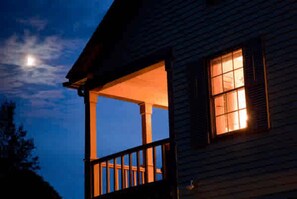 A wooden house with a porch and a window lit from inside. - The Waterford Inne (Waterford)